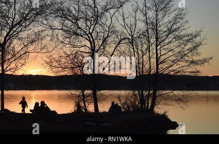 München, Deutschland. 16. Februar 2019, Bayern, München: Wanderer genießen die letzten Strahlen der untergehenden Sonne im Starnberger See. Foto: Angelika Warmuth/dpa Stockfoto