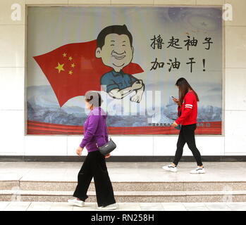 Dunhuang, Gansu, China. 30 Sep, 2018. Chinesische Spaziergang, vorbei an einem öffentlichen Zeichen erinnern, dass Präsident Xi Jinping macht das Land stärker, wenn Menschen schwer in Dunhuang, Provinz Gansu, am 30. September 2018. Xi hat seine eigene politische Ideologie erstellt wurden, in einem Schritt zur Verankerung seiner Stellung an der Spitze der Kommunistischen Partei. Credit: Stephen Rasierer/ZUMA Draht/Alamy leben Nachrichten Stockfoto