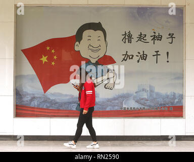 Dunhuang, Gansu, China. 30 Sep, 2018. Chinesische Spaziergang, vorbei an einem öffentlichen Zeichen erinnern, dass Präsident Xi Jinping macht das Land stärker, wenn Menschen schwer in Dunhuang, Provinz Gansu, am 30. September 2018. Xi hat seine eigene politische Ideologie erstellt wurden, in einem Schritt zur Verankerung seiner Stellung an der Spitze der Kommunistischen Partei. Credit: Stephen Rasierer/ZUMA Draht/Alamy leben Nachrichten Stockfoto