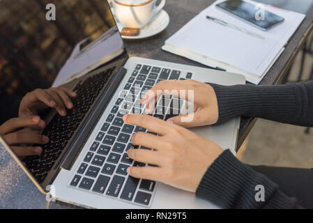 Frau Hände mit Laptop outdoor im sonnigen Morgen, Notebook, Smartphone und heißem Kaffee für neue Arbeitstag Stockfoto