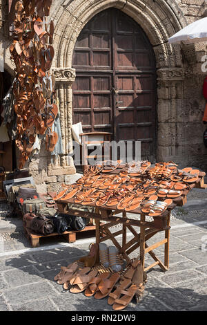 Die Insel Rhodos, Griechenland - 12. September 2018. Griechische Handgemachte Ledersandalen hängenden außerhalb einer Shop in einer ruhigen Straße in der Altstadt von Rhodos, Dodekanes Isla Stockfoto