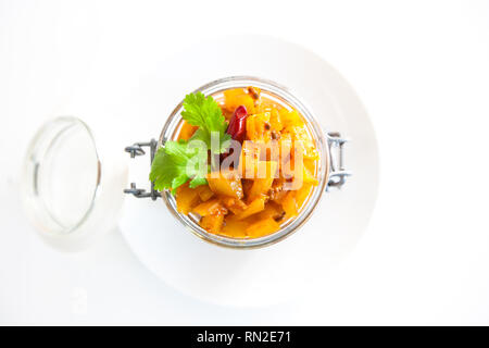 Hausgemachte Mango Chutney in einem Glas mit Gewürzen und Mangos auf weißem Hintergrund Stockfoto