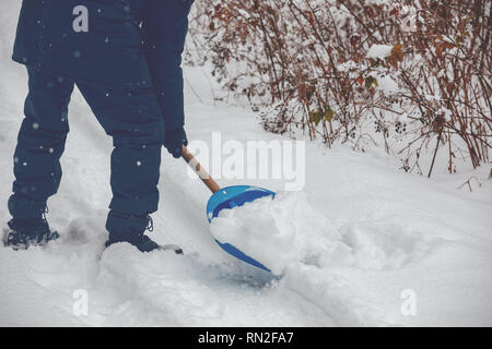 Ein Mann mit einer Schaufel reinigt die Straße vom Schnee Stockfoto