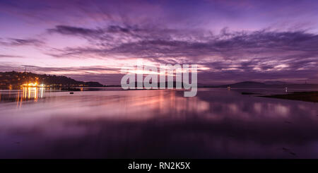 Sonne über Oban Bay in den westlichen Highlands von Schottland, einschließlich die Lichter der Stadt Oban und die Küste von Kerrera Insel. Stockfoto