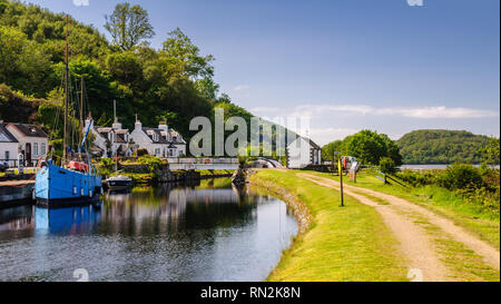 Crinan, Schottland, Großbritannien - 3. Juni 2011: Eine kleine Yacht und Boot sind neben traditionellen Cottages in der crinan Canal in der West Highlands o günstig Stockfoto