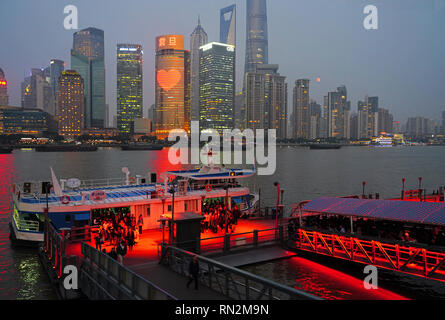 Ferry Terminal Passagiere auf Pier in der Nacht Anreise mit der Skyline von Pudong über den Fluss Huangpu in Shanghai. Stockfoto