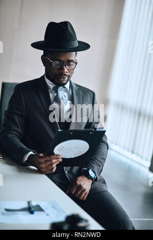 Business Mann sitzt und Suchen von Dokumenten in Ordner. Netter Kerl hält ein contrect. Schreibarbeit. Closeup Portrait Stockfoto