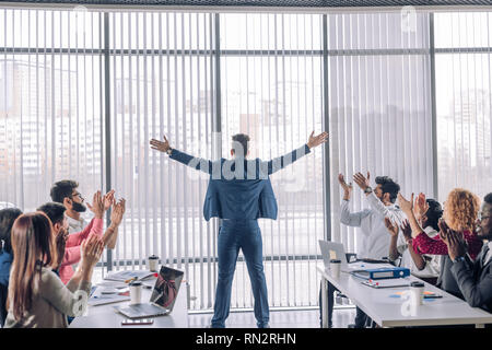 Business, Erfolg, Geste und Personen Konzept - auf der Rückseite der jubelnden Geschäftsmann Anheben der Arme und feiert Triumph über Panoramablick office Fenster und Stockfoto
