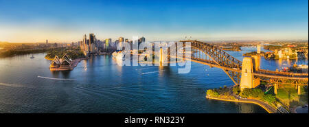 Warme und weiche Morgensonne Licht auf großen Stadt Sydney CBD Grenzsteine um Sydney Harbour von oben betrachtet - Luftbild breites Panorama mit Blick auf Cicrular Quay Stockfoto