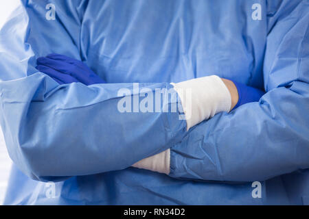 Chirurg Arzt in sterilen Handschuhen Vorbereitung für den Einsatz im Krankenhaus. Er trägt eine chirurgische Gap und blauem Kleid Stockfoto