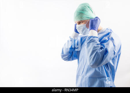 Chirurg Arzt in sterilen Handschuhen Vorbereitung für den Einsatz im Krankenhaus. Er trägt eine chirurgische Gap und blauem Kleid Stockfoto