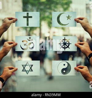 Religion Konflikte als globales Thema Konzept. Menschliche Hände halten Sie anderes Papier mit Glaube Symbole überfüllten Straße. Beziehungen zwischen unterscheiden Stockfoto