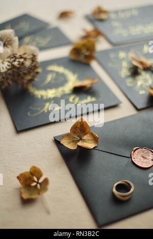 Grenze der Hochzeit Handwerk Briefumschläge auf Schwarzen Tisch. Ansicht von oben auf dem Papier Karten und geschriebenen Text. Denkwürdige Daten Organisation Konzept. Datum speichern backgro Stockfoto