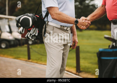 7/8 Schuß von älteren Golf Spieler die Hände schütteln, wenn auf einem Golfplatz. Golfspieler Begrüßung mit handschlag vor dem Spiel. Stockfoto