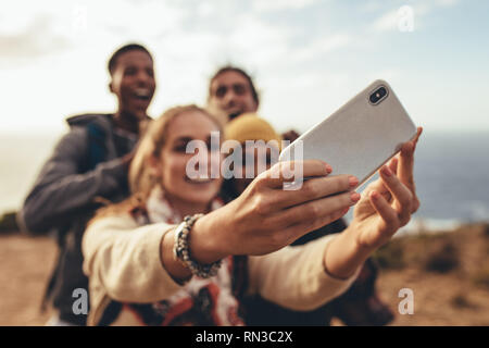 Frau unter selfie mit Freunden auf Wanderung. Fokus auf weibliche Hände halten ein smart phone und unter selfie mit Freunden im Freien. Stockfoto