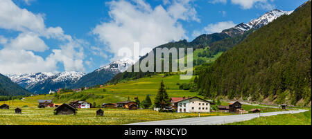 Sommer Alpine Land Bergblick mit Wiese und Straße zum Dorf (Österreich) Stockfoto