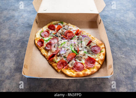 Pizza mit verschiedenen Toppings im Lieferumfang box Stockfoto