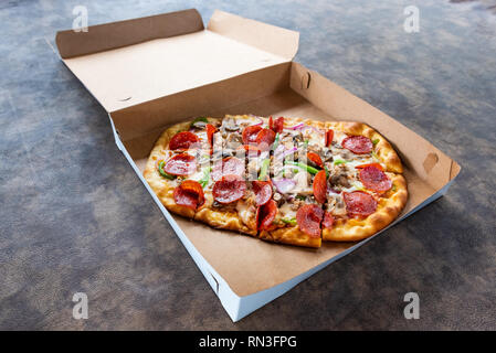 Pizza mit verschiedenen Toppings im Lieferumfang box Stockfoto