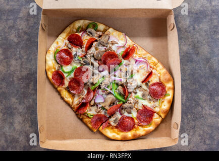 Pizza mit verschiedenen Toppings im Lieferumfang box Stockfoto