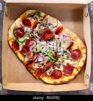 Pizza mit verschiedenen Toppings im Lieferumfang box Stockfoto