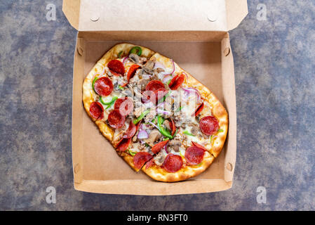 Pizza mit verschiedenen Toppings im Lieferumfang box Stockfoto