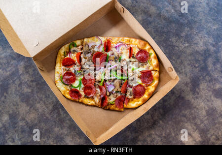 Pizza mit verschiedenen Toppings im Lieferumfang box Stockfoto