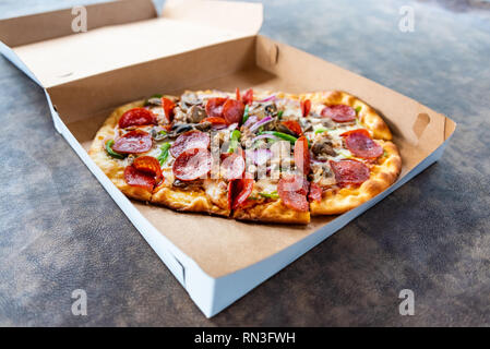 Pizza mit verschiedenen Toppings im Lieferumfang box Stockfoto