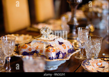 Porzellan und Gläser auf einem antiken gedeckten Tisch bei Scotney Castle im Süden von England. Stockfoto