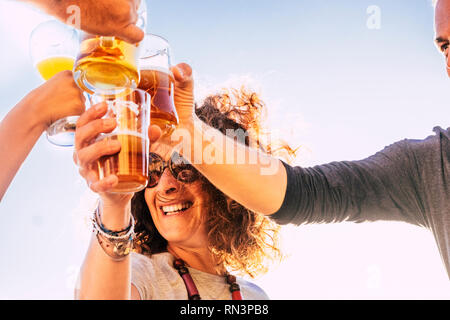 Nahaufnahme von Menschen Toasten und klirren zusammen mit glücklichen und Freude und Spaß-fröhliche Menschen mit Bier und Getränke in Freundschaft lachen - mi Stockfoto