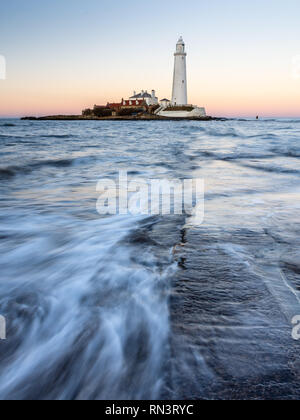 Wellen, Strömung gegenüber der St. Maria Island Causeway in der Dämmerung, mit St Mary's Leuchtturm hinter, auf der Whitley Bay Küste von Tyneside. Stockfoto