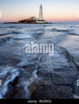 Wellen, Strömung gegenüber der St. Maria Island Causeway in der Dämmerung, mit St Mary's Leuchtturm hinter, auf der Whitley Bay Küste von Tyneside. Stockfoto