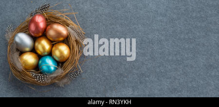 Frohe Ostern Urlaub gruss Symbol stilvollen natürlichen Holz- Gras Nest mit bunten Wachtel Eier und Federn auf grauem Stoff Hintergrund mit Kopie Raum Stockfoto