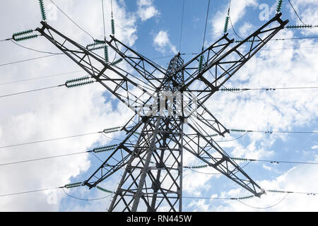 Nahaufnahme eines Strommast Bau- und Stromleitungen gegen einen blauen Himmel mit einigen Wolken Stockfoto