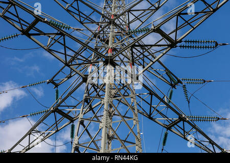 Nahaufnahme eines Strommast Bau- und Stromleitungen gegen einen blauen Himmel mit einigen Wolken Stockfoto