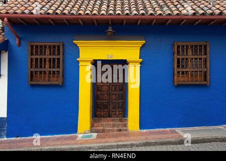 Elegante koloniale Fassade mit Holz geschnitzte Tür und Blau-gelbe Wand (komplementärer Farbkontrast) in La Candelaria. Bogota, Kolumbien. Sep 2018 Stockfoto