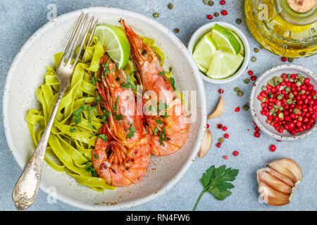 Gebratene Riesengarnelen mit Knoblauch, Pfeffer, Zitrone und Petersilie (Koriander). Große Garnelen. Scampi. Köstliches Abendessen mit Pasta Tagliatelle mit Spinat. Sel Stockfoto