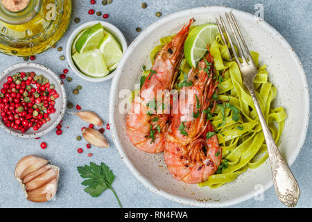 Gebratene Riesengarnelen mit Knoblauch, Pfeffer, Zitrone und Petersilie (Koriander). Große Garnelen. Scampi. Köstliches Abendessen mit Pasta Tagliatelle mit Spinat. Sel Stockfoto