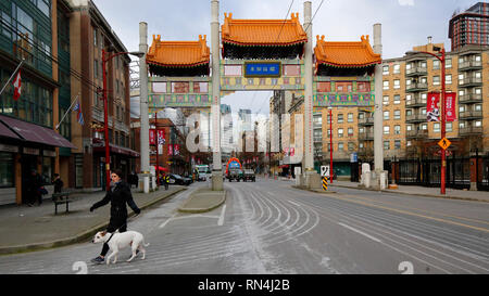 Eine Person, die mit einem Hund in der Nähe von Vancouver Chinatown Millenium Gate, Vancouver, British Columbia, Kanada spaziert Stockfoto