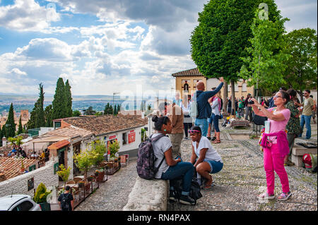 Touristen nehmen Bilder von sich im Mirador San Nicolas, einem kleinen Platz mit Blick über die Alhambra in Granada. Stockfoto