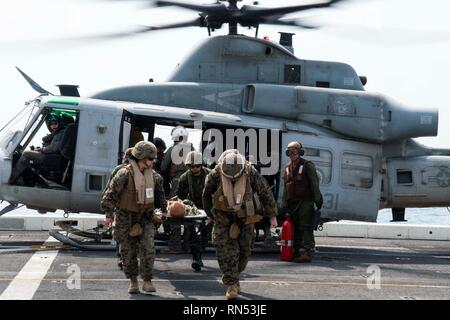 190215-N-DX 072-1201 GOLF VON THAILAND (Feb. 15, 2019) - U.S. Navy Hospital corpsmen und Royal Thai Marines tragen einen simulierten Patienten von einem UH-1Y Huey Hubschrauber, der Marine Light Attack Helicopter Squadron (HMLA) 267 zugeordnet, auf dem Flugdeck des amphibious Transport dock Schiff USS Green Bay LPD (20) Während ein Unfall Evakuierungsübung. Green Bay, Teil der Wasp amphibischen bereit, Gruppe, mit Eingeschifft 31 Marine Expeditionary Unit (MEU), in Thailand, die in der Übung Cobra Gold 2019 zu beteiligen. Cobra Gold ist eine multinationale Übung von Thailand und den Vereinigten Staaten gesponsert. Stockfoto