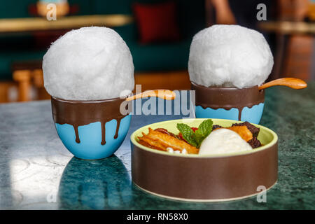 Zwei blaue Keramik Tassen heißer Schokolade garniert mit fairy Glasschlacke und eine Schale mit Churros mit Eis auf dem Tisch. Stockfoto