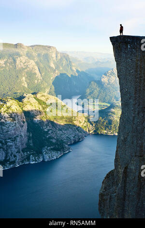 Ein einsamer Mann steht oben auf der Kanzel Rock/Preikestolen oder Prekestolen mit Blick auf den Lysefjord in Norwegen Stockfoto