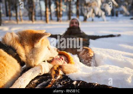 Mädchen spielen mit Hund im Schnee Stockfoto