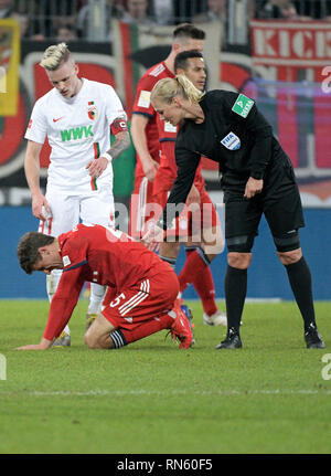 15. Februar 2019, Bayern, Augsburg: Fußball: Bundesliga, FC Augsburg - FC Bayern München, den 22. Spieltag in der Wwk-Arena. Schiedsrichter Bibiana Steinhaus beugt sich über Münchener Thomas Müller (M). Der Augsburger Philipp Max (l) Uhren. Weil Steinhaus das Spiel geleitet hat, die Übertragung des Spiels auf iranischen Staatsfernsehen IRIB wird gesagt abgebrochen zu haben. Das berichtet von verschiedenen Iranischen Medien am Samstag (16.02.2019). Foto: Stefan Puchner/dpa - WICHTIGER HINWEIS: In Übereinstimmung mit den Anforderungen der DFL Deutsche Fußball Liga oder der DFB Deutscher Fußball-Bund ist es untersagt, zu verwenden, oder Stockfoto