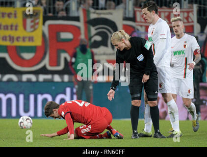 15. Februar 2019, Bayern, Augsburg: Fußball: Bundesliga, FC Augsburg - FC Bayern München, den 22. Spieltag in der Wwk-Arena. Schiedsrichter Bibiana Steinhaus beugt sich über Münchener Thomas Müller (l). Der Augsburger Philipp Max (r) und Michael Gregoritsch beobachten. Weil Steinhaus das Spiel geleitet hat, die Übertragung des Spiels auf iranischen Staatsfernsehen IRIB wird gesagt abgebrochen zu haben. Das berichtet von verschiedenen Iranischen Medien am Samstag (16.02.2019) Foto: Stefan Puchner/dpa - WICHTIGER HINWEIS: In Übereinstimmung mit den Anforderungen der DFL Deutsche Fußball Liga oder der DFB Deutscher Fußball-Bund, es ist Stockfoto