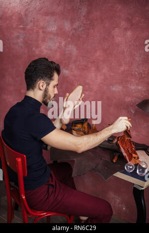 Handwerker, die im Besitz einer Futter und Innensohle aus Leder am Arbeitsplatz. close up Side View Photo. handsmade Einlegesohlen für Kunden Stockfoto