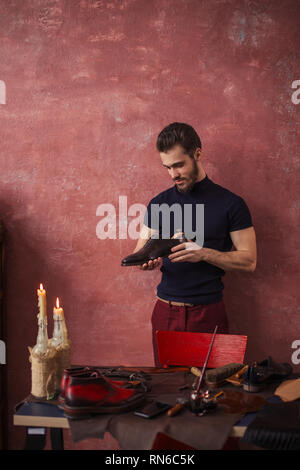 Fröhliche Schuster seine bevorzugten italienische Schuhe Holding am Arbeitsplatz. nach oben Foto schliessen. Stockfoto