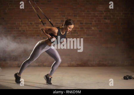 Fitness Frau trainin am TRX in der Turnhalle, Sprinter Übung starten, wo Muskeln stabilisieren ausgebildet sind und der ganze Körper arbeitet, die Stockfoto