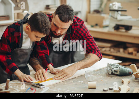 Neugierige kleine Junge Klassen der Tischlerei aus berühmten WOODWORKER. Hobby wächst in der Arbeit von Berufung. Stockfoto