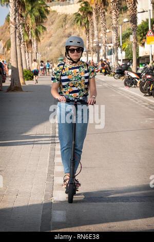 Eine attraktive junge Dame, einen elektroroller auf der Jim Spitz Radweg in Tel Aviv, in der Nähe der mediterranen Meer. Stockfoto